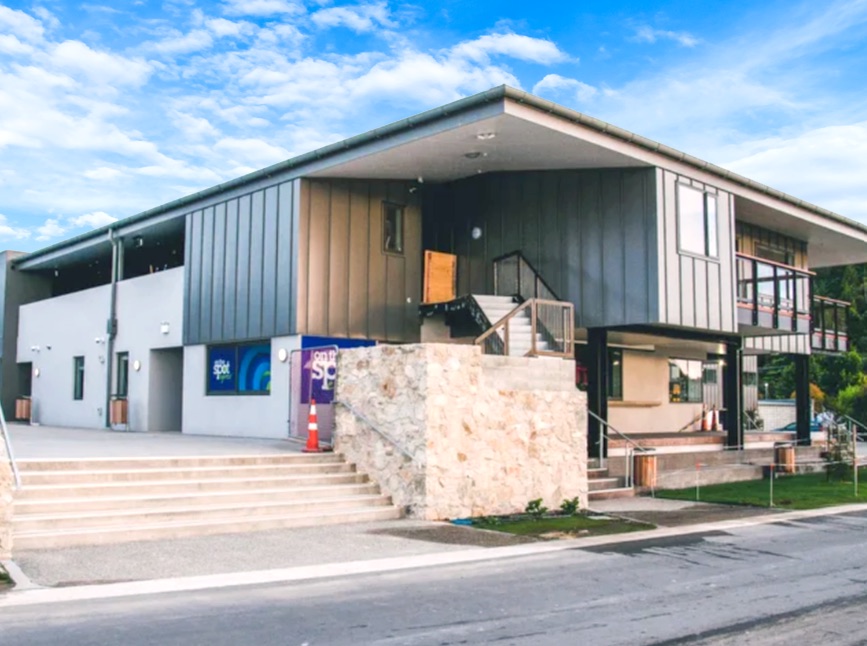 Kaiteriteri accommodation building with grey and timber cladding, a stone wall and wide steps